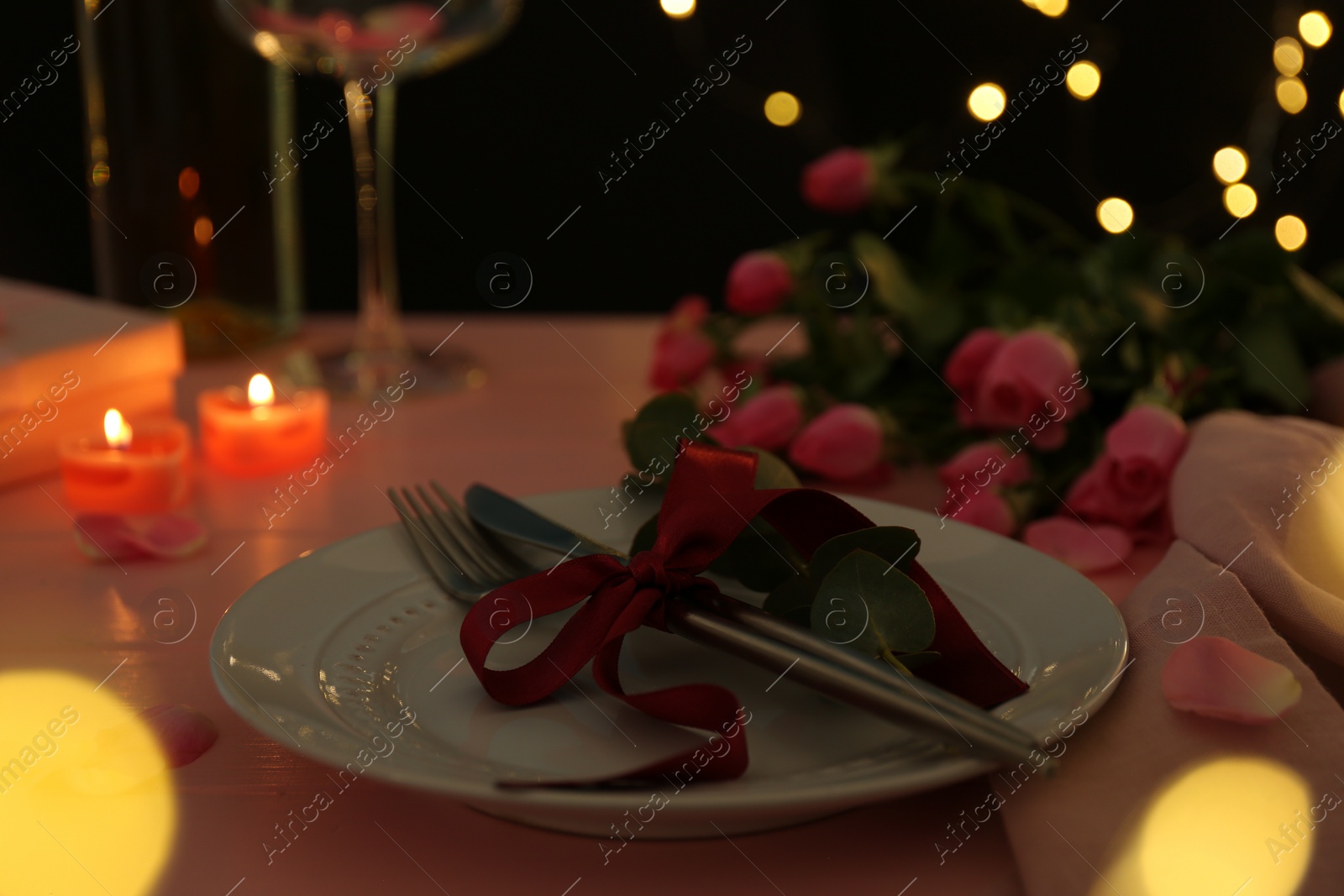 Photo of Place setting with roses and candles on pink wooden table, closeup. Romantic dinner