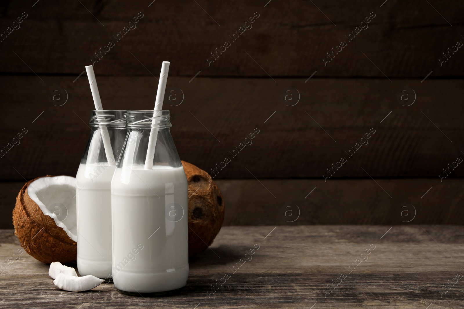 Photo of Delicious vegan milk and coconuts on wooden table, space for text