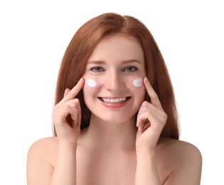 Photo of Smiling woman with freckles applying cream onto her face against white background