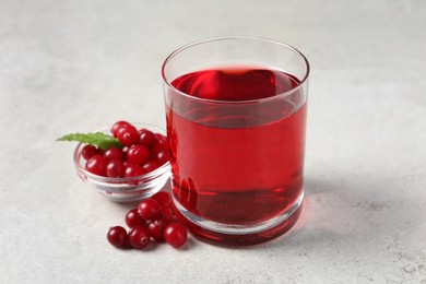 Photo of Tasty refreshing cranberry juice, mint and fresh berries on light table
