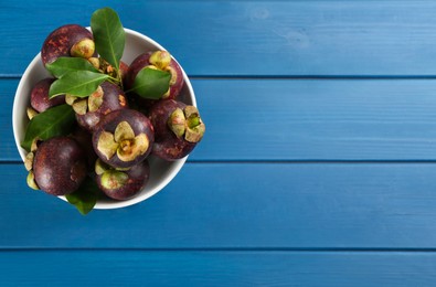 Photo of Delicious tropical mangosteens on blue wooden table, top view. Space for text