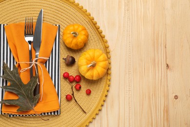 Photo of Cutlery, napkins and autumn decoration on wooden background, flat lay with space for text. Table setting