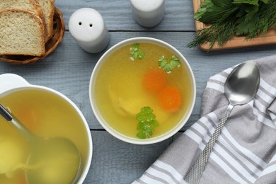 Photo of Delicious chicken bouillon with carrot and parsley on grey wooden table, flat lay