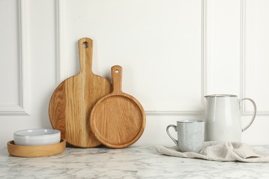 Photo of Wooden cutting boards, dishware and towel on white marble table