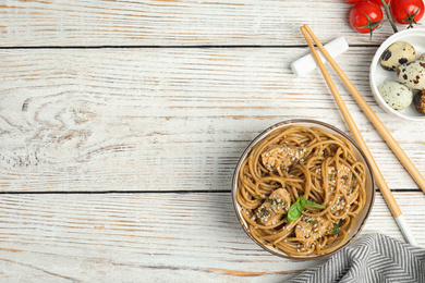 Tasty buckwheat noodles with meat served on white wooden table, flat lay. Space for text