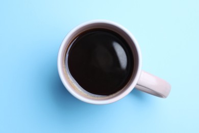 Photo of Fresh aromatic coffee in mug on light blue background, top view