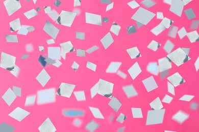 Shiny confetti falling down on pink background