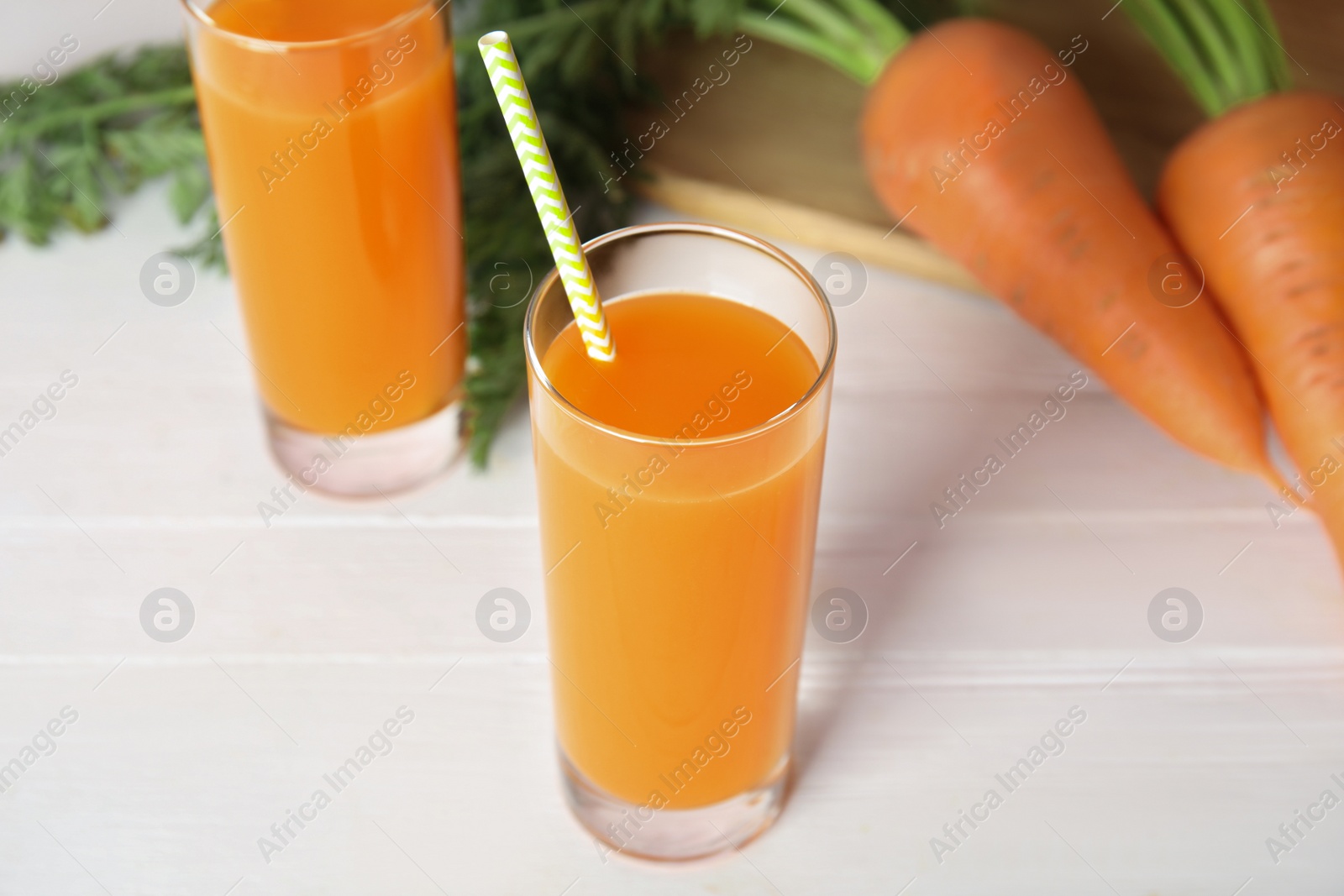 Photo of Freshly made carrot juice on white wooden table