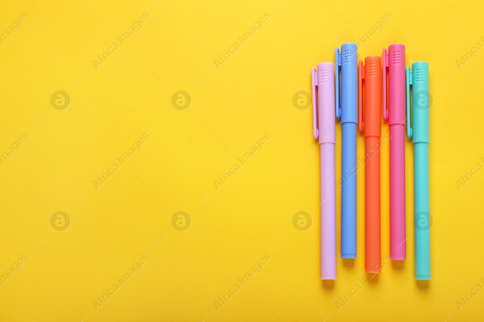 Photo of Many colorful markers on yellow background, flat lay. Space for text