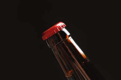 Photo of Bottle of tasty cold beer on black background, closeup