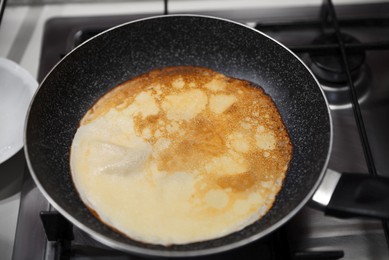 Photo of Frying delicious crepe on pan in kitchen, closeup