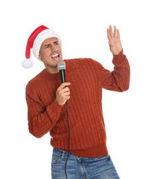 Emotional man in Santa Claus hat singing with microphone on white background. Christmas music