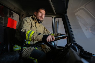 Firefighter in uniform driving modern fire truck