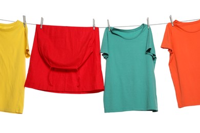 Photo of Different bright clothes drying on washing line against white background