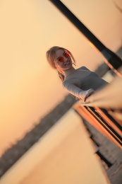 Silhouette of young woman leaning on railing at sunset