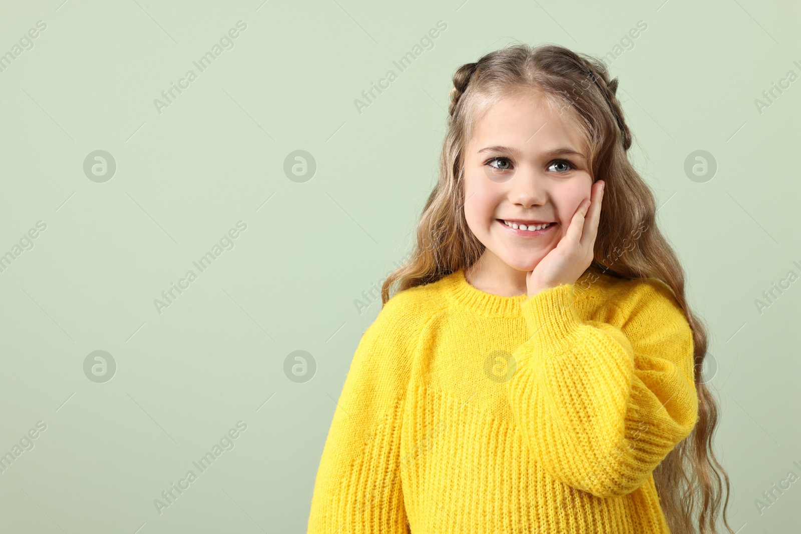 Photo of Cute little girl with braided hair on light green background. Space for text