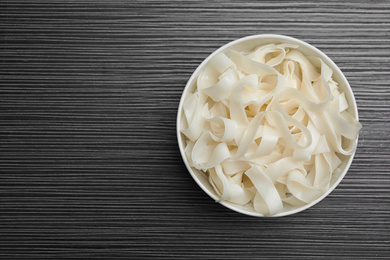 Photo of Tasty rice noodles on black wooden table, top view. Space for text