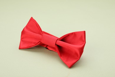 Photo of Stylish red bow tie on pale green background
