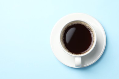 Photo of Cup of aromatic coffee on light blue background, top view. Space for text