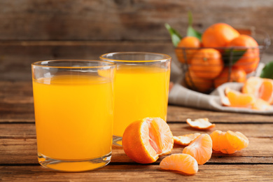 Photo of Glasses of fresh tangerine juice and fruits on wooden table