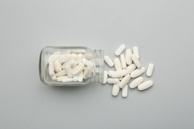 Photo of Vitamin pills and bottle on grey background, top view