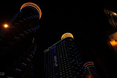 Photo of BATUMI, GEORGIA - JUNE 09, 2022: Night cityscape with illuminated buildings, low angle view