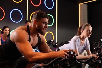 Group of people training on exercise bikes in fitness club