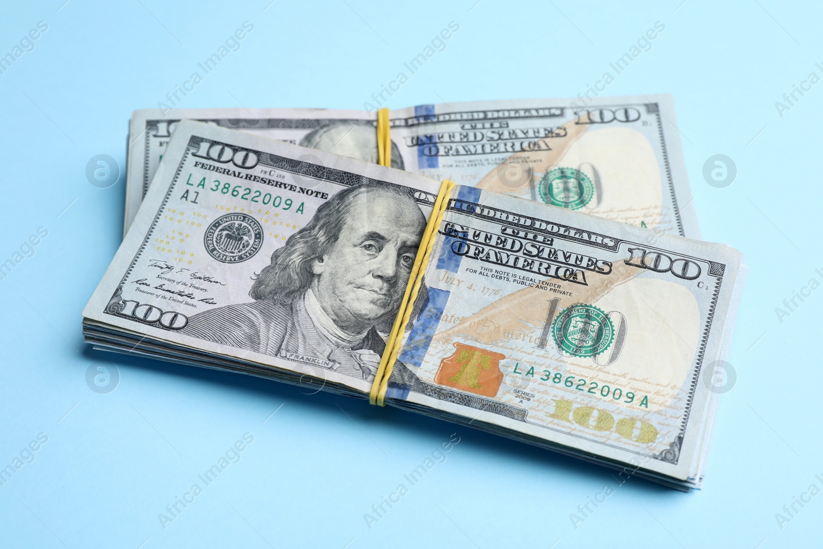 Photo of Bundles of dollar banknotes on light blue background