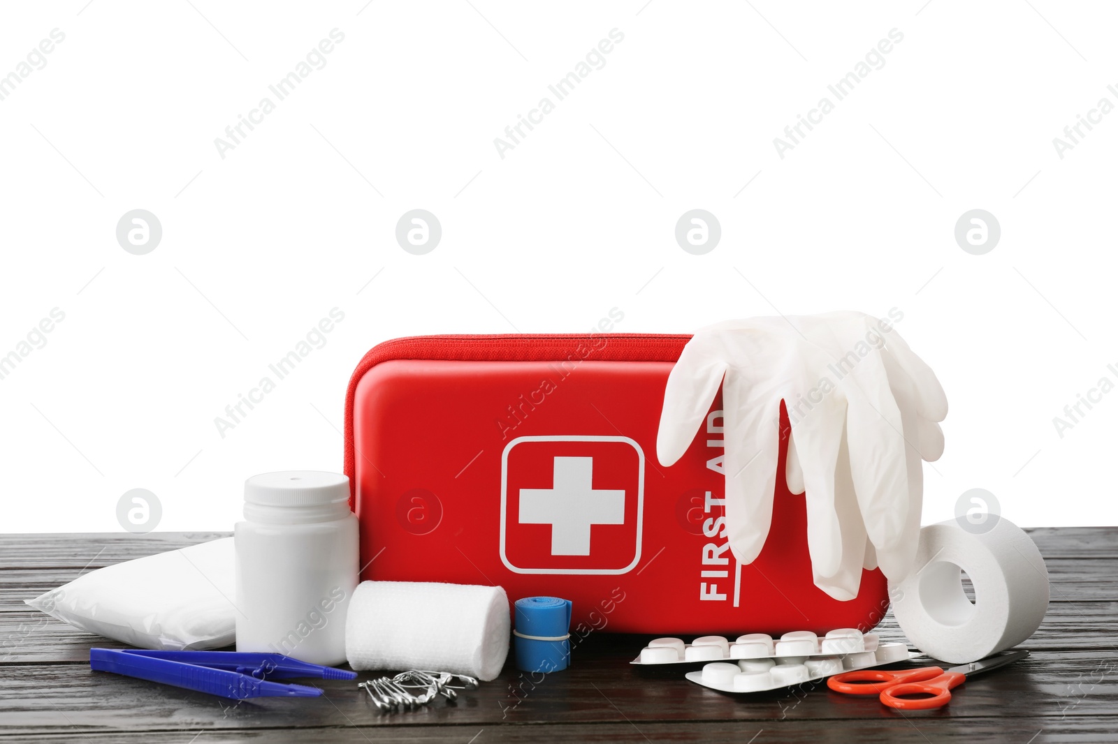 Photo of First aid kit, scissors, gloves, pills, plastic forceps and elastic bandage on wooden table against white background