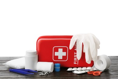 Photo of First aid kit, scissors, gloves, pills, plastic forceps and elastic bandage on wooden table against white background