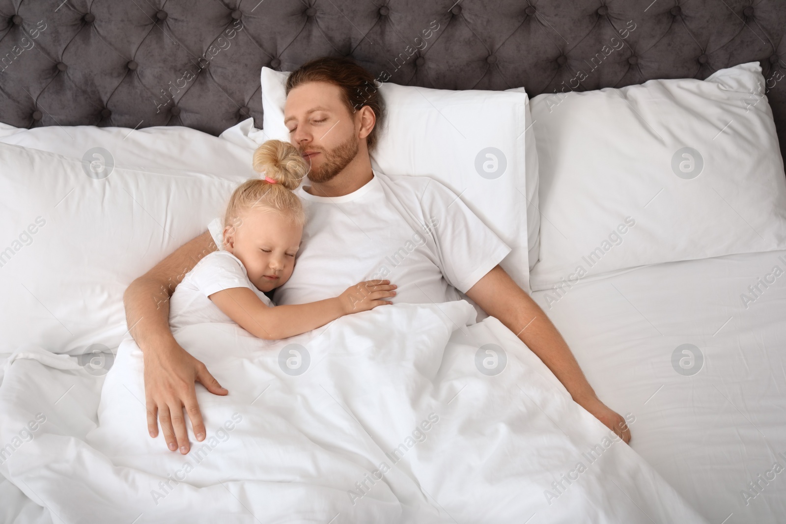 Photo of Father and his cute daughter sleeping in bed. Nap time