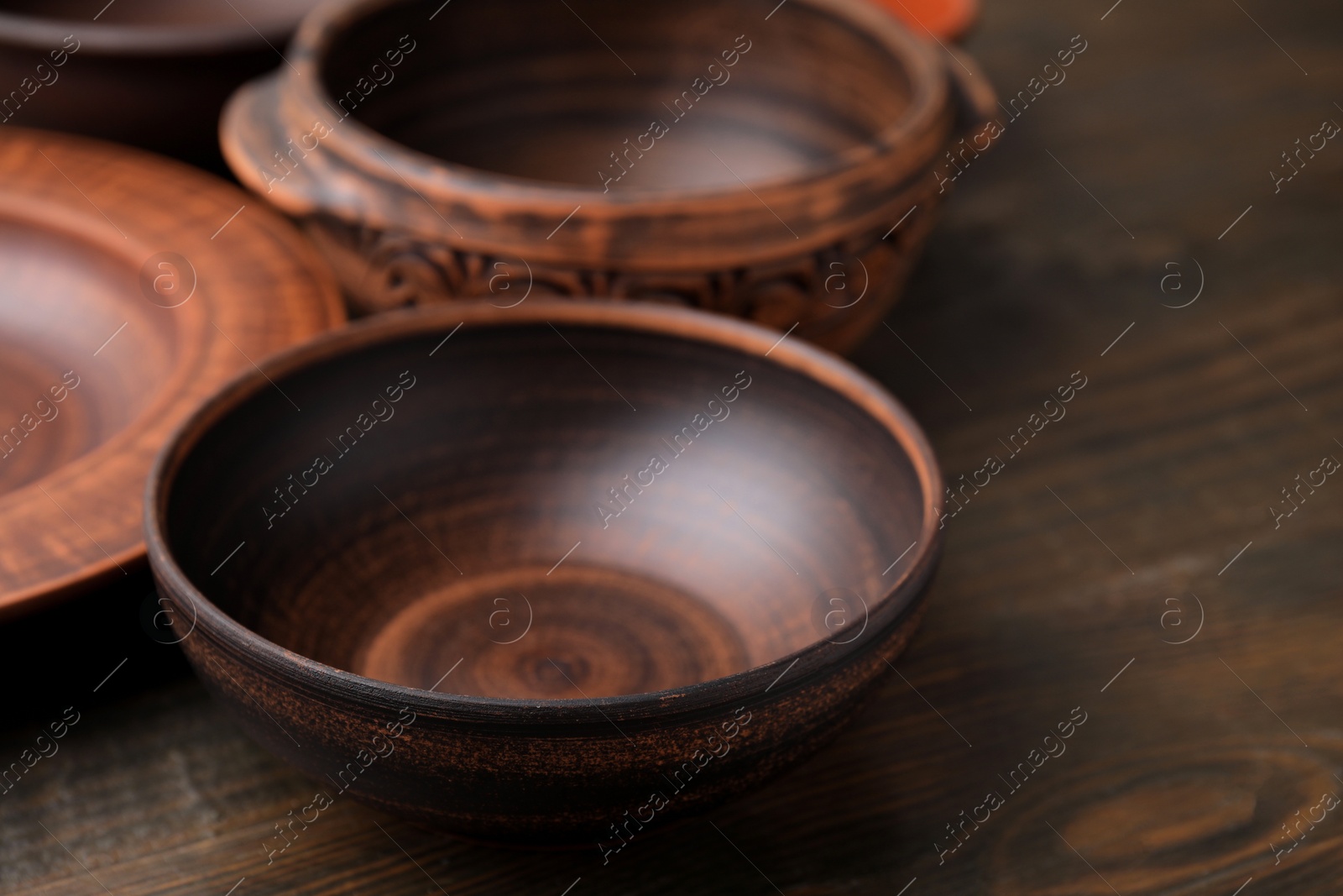 Photo of Set of clay dishes on wooden table, closeup. Cooking utensils