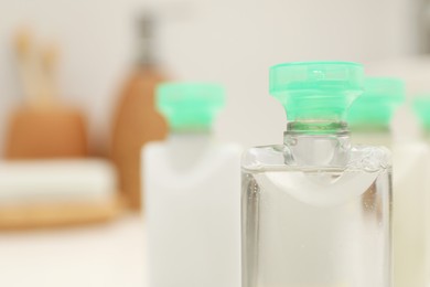 Mini bottles of cosmetic products on blurred background, closeup. Space for text