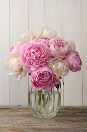 Photo of Beautiful peonies in vase on wooden table