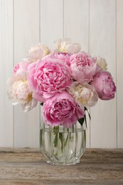 Beautiful peonies in vase on wooden table