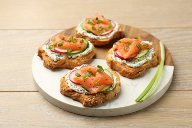 Photo of Tasty canapes with salmon served on wooden table