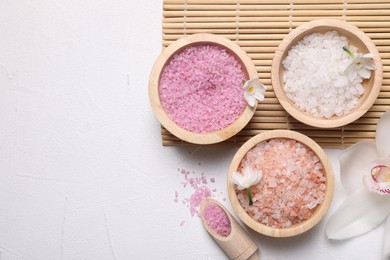 Photo of Different types of sea salt and flowers on light table, flat lay. Spa products