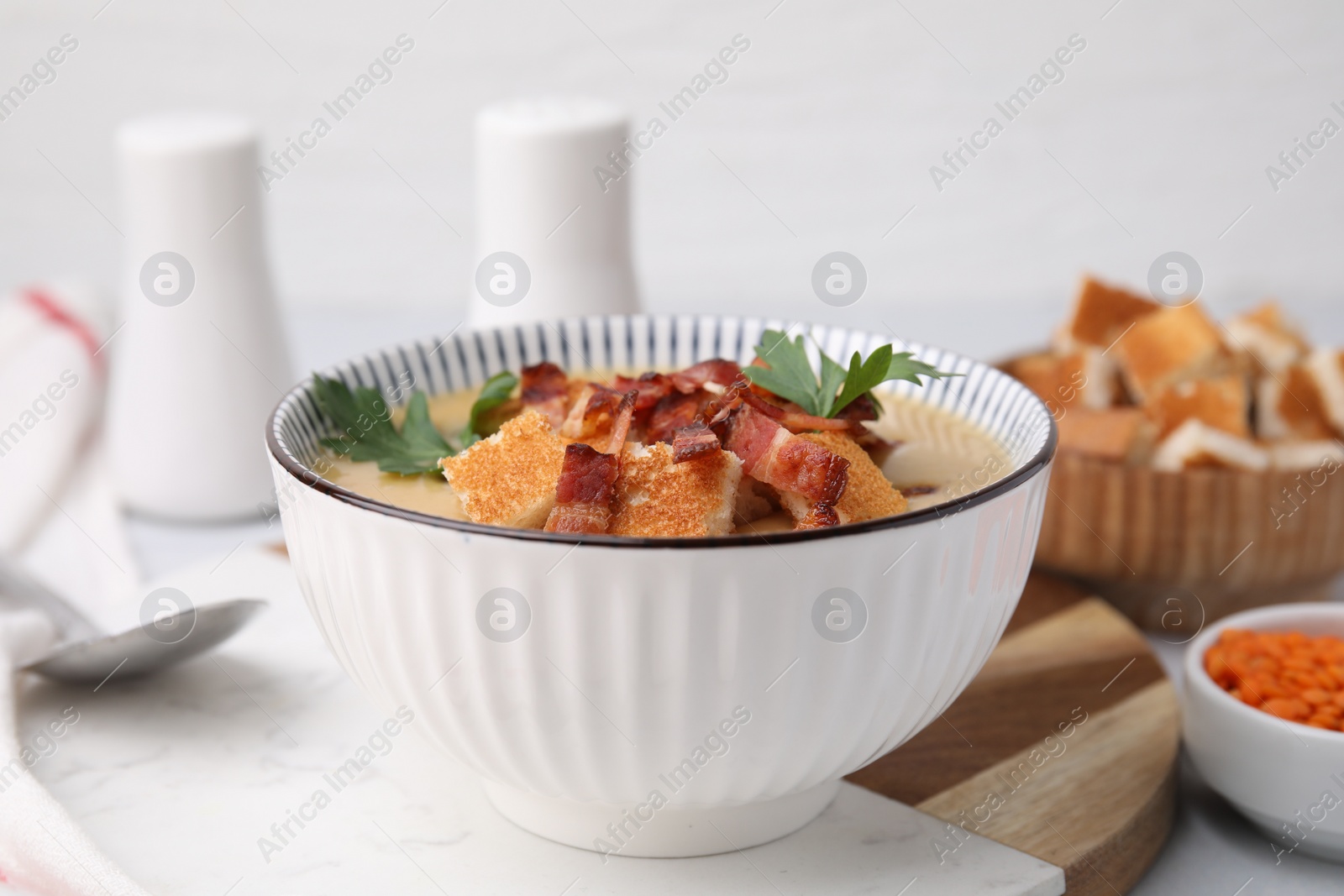 Photo of Delicious lentil soup with bacon and parsley in bowl on table