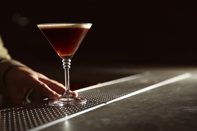 Photo of Barman serving espresso martini cocktail at counter, closeup. Space for text