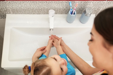 Photo of Mother and daughter washing hands in bathroom at home, above view