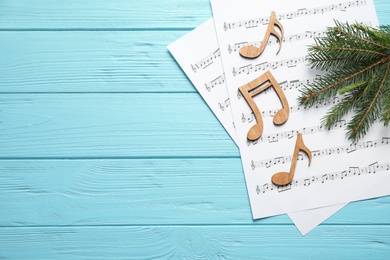 Photo of Christmas tree branch, notes and music sheets on blue wooden table, flat lay with space for text