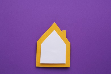 Paper house on purple background, top view. Space for text