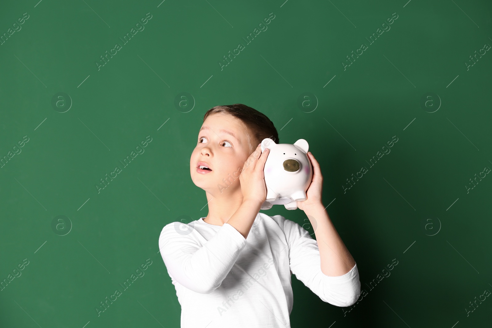 Photo of Little boy with piggy bank on color background