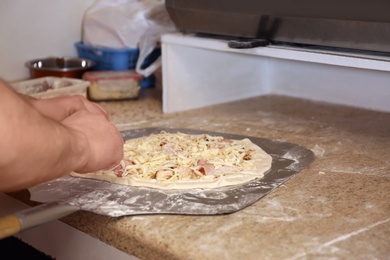 Photo of Man preparing pizza at table, closeup. Oven recipe