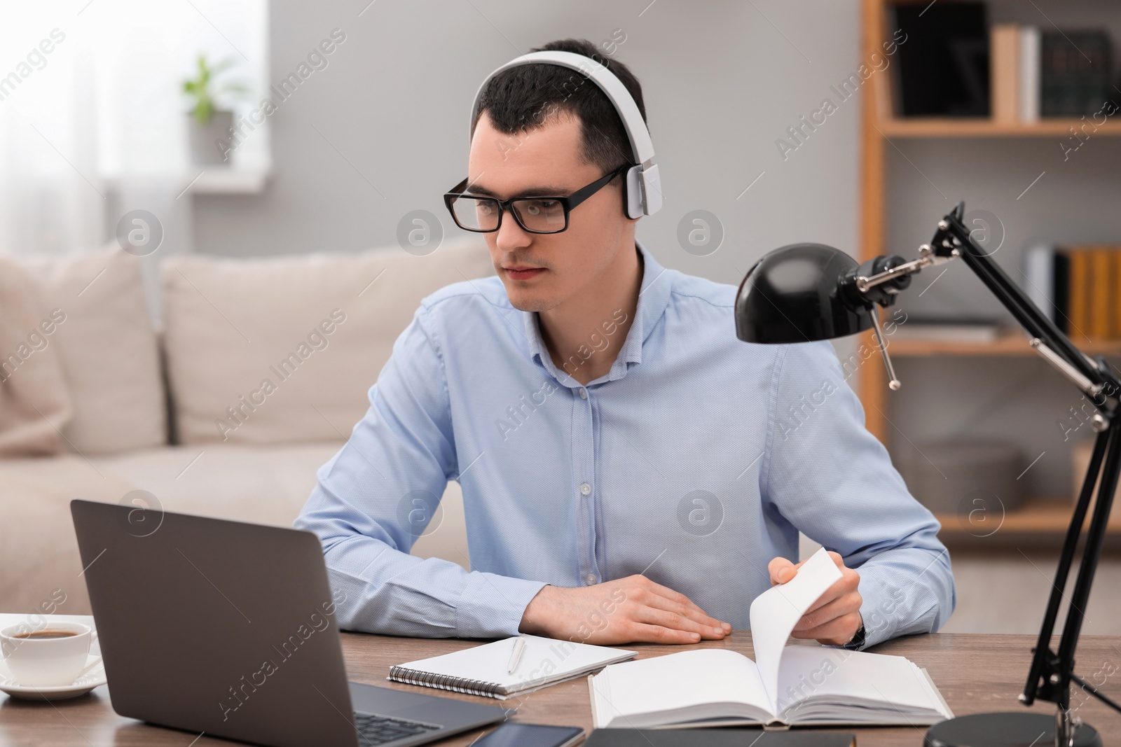 Photo of E-learning. Young man using laptop during online lesson at table indoors.