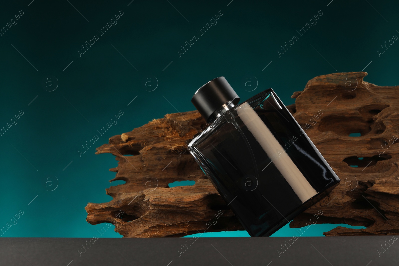 Photo of Luxury men`s perfume in bottle on grey table against color background, space for text