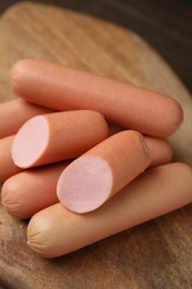 Photo of Whole and cut delicious boiled sausages on table, closeup