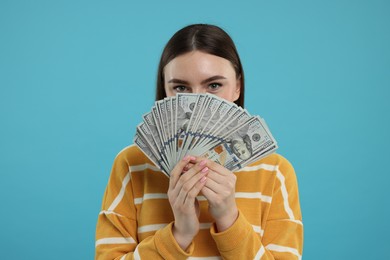 Woman with dollar banknotes on light blue background