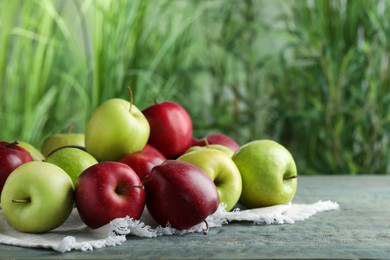 Photo of Fresh ripe red and green apples on light blue wooden table outdoors, space for text