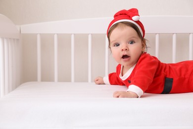 Photo of Cute baby wearing festive Christmas costume in crib. Space for text